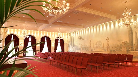 Salle avec chaises, lustres, plantes, et décorations murales.