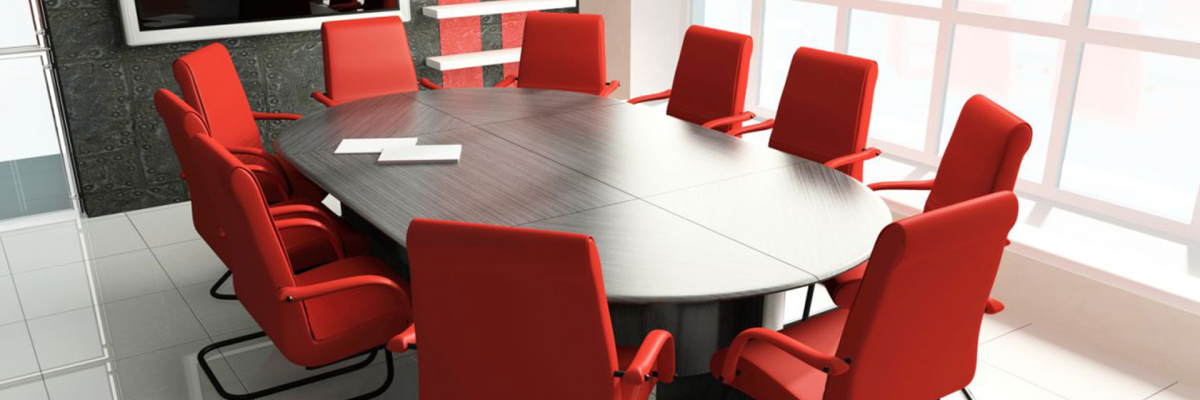 Salle de réunion avec table, chaises, tableau et étagères.