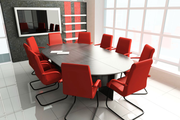 Salle de réunion avec table, chaises, tableau et étagères.